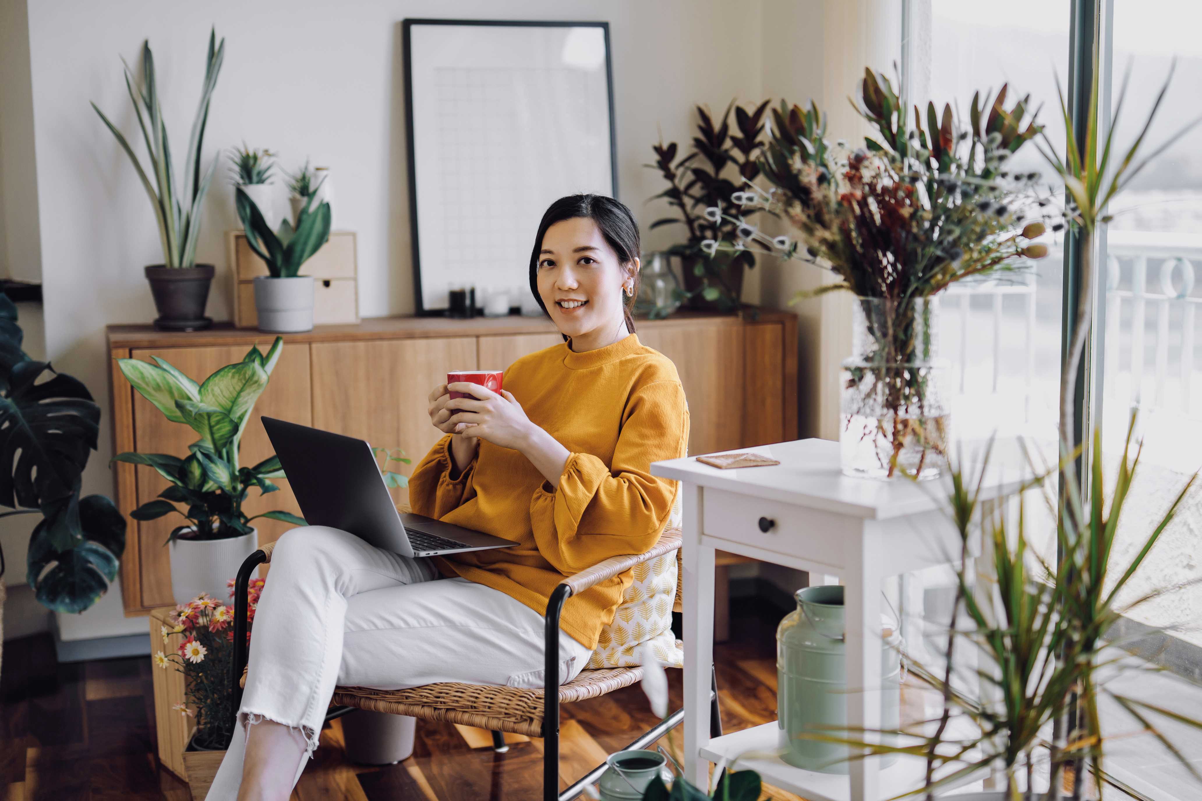 Women in yellow short holding coffee working on the computer